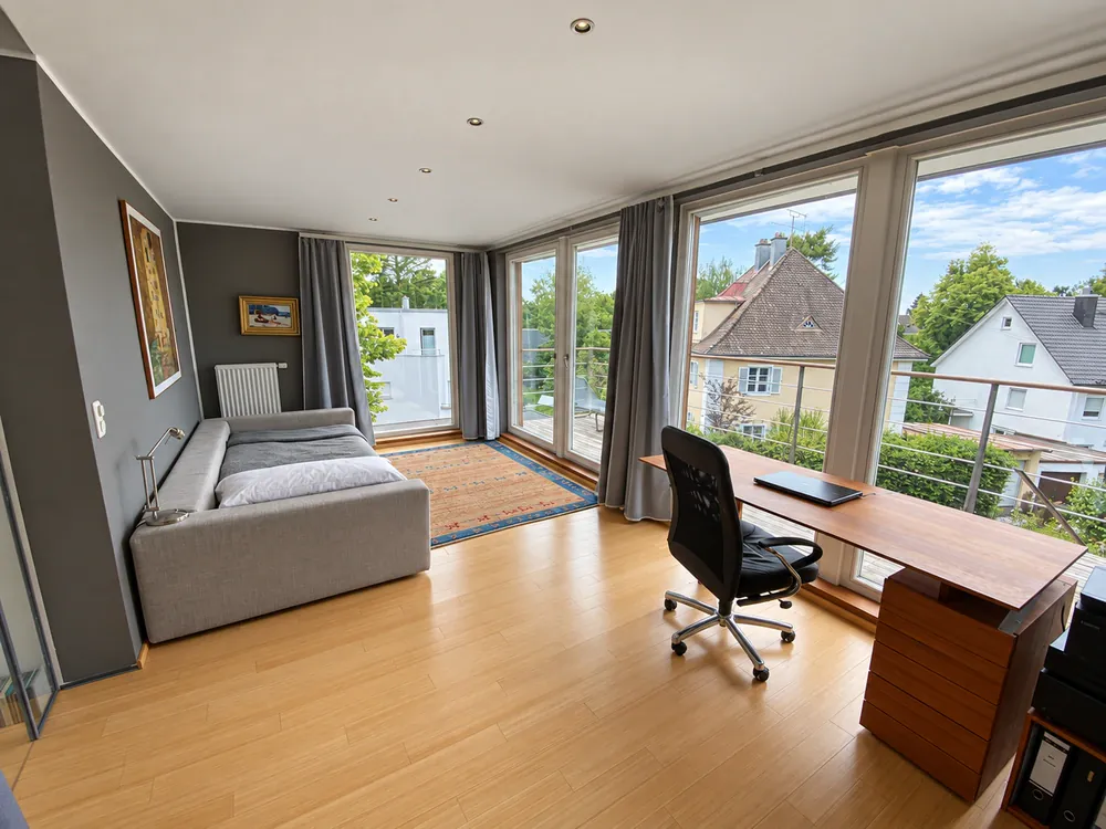 Oberes Zimmer mit Sofa, Schreibtisch und Fensterfront